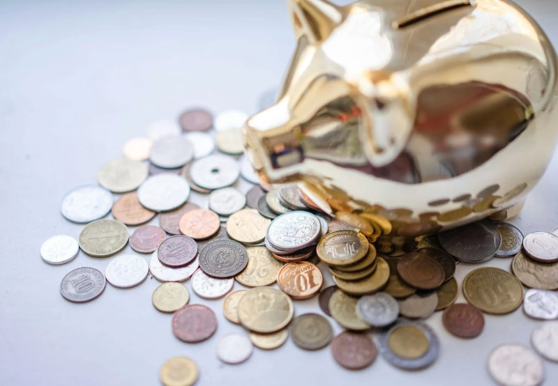 Gold piggy bank with various gold coins around it